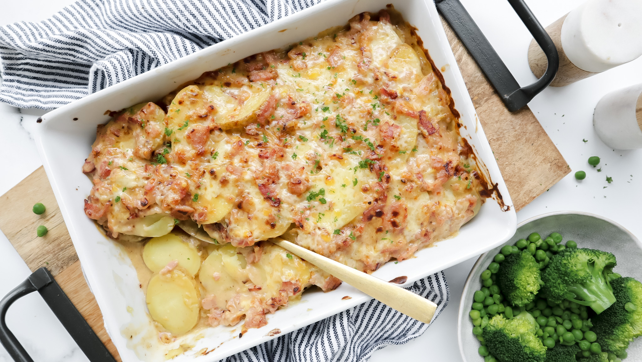 Cheesy bacon and potato bake with a golden crust, served alongside fresh steamed green beans and broccoli.