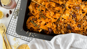 Bowl of pork and beef ragu with wide pappardelle pasta, topped with fresh parsley and Parmesan cheese.