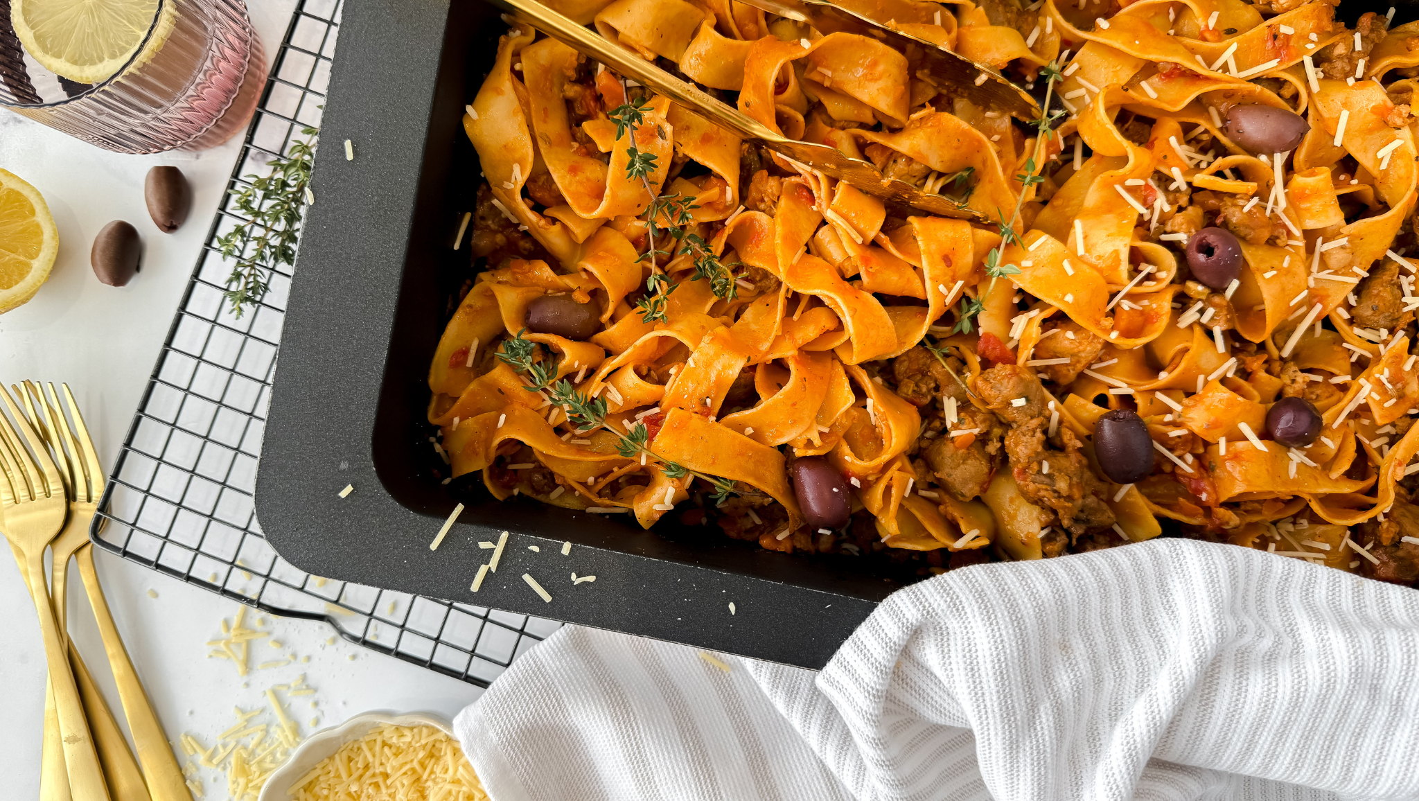 Bowl of pork and beef ragu with wide pappardelle pasta, topped with fresh parsley and Parmesan cheese.